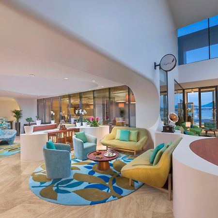 The Retreat Palm Dubai Mgallery By Sofitel Kültér fotó The photo depicts a modern and stylish interior space, likely a lobby or lounge area. It features a variety of seating arrangements, including colorful chairs and a couch, all arranged around a central coffee table. The floor is adorned with a large,