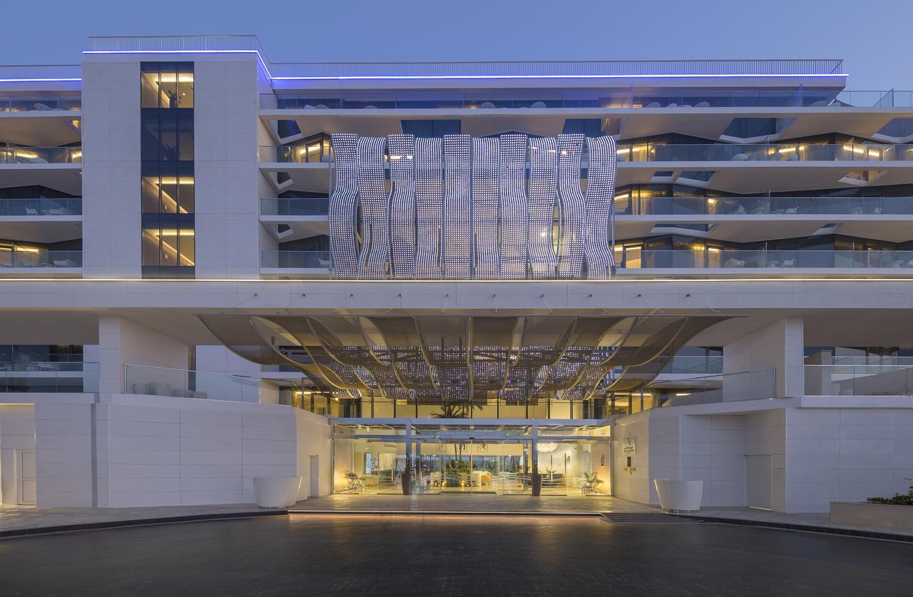 The Retreat Palm Dubai Mgallery By Sofitel Kültér fotó The photo shows a modern building with a sleek architectural design. It features multiple stories and a striking entrance that has a unique, artistic canopy overhead. The exterior is primarily white, highlighting clean lines and a contemporary aesthe